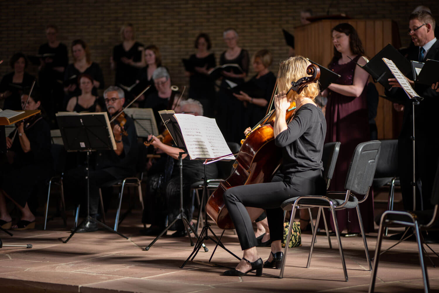 Ein Orchester spielt, Fokus auf eine Cellistin in einem Konzertsaal.