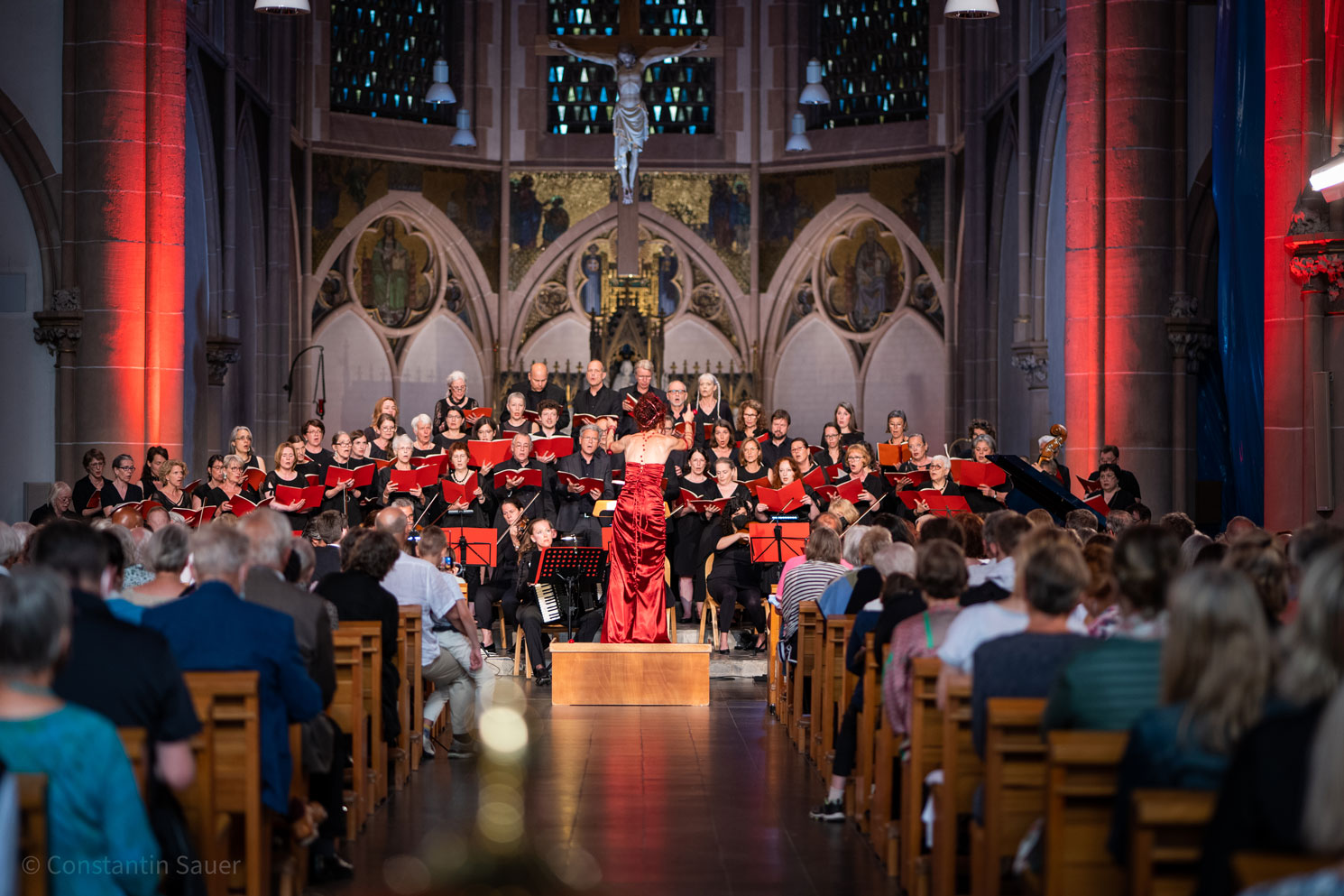 Konzertaufführung in einer Kirche mit Chormitgliedern und Orchester auf der Bühne.