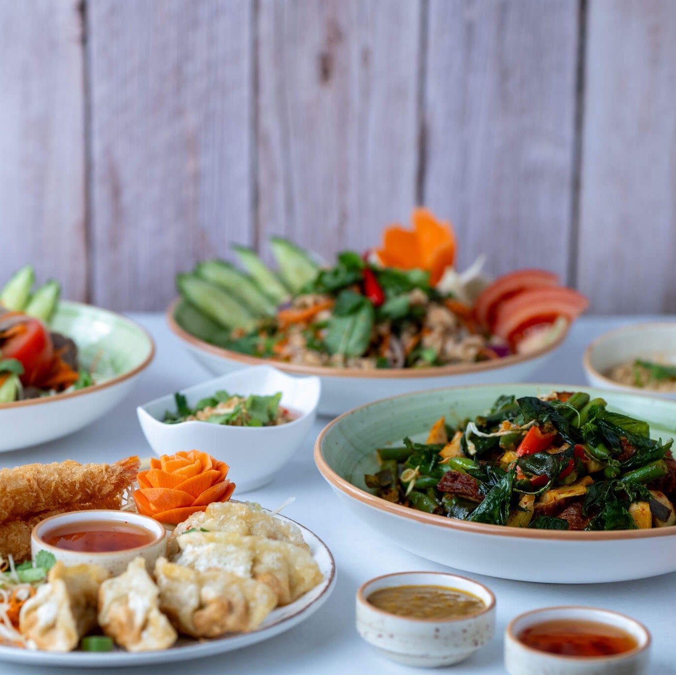 Bunte, asiatische Gerichte mit Gemüse, Sushi, Dip-Saucen und frischen Kräutern.