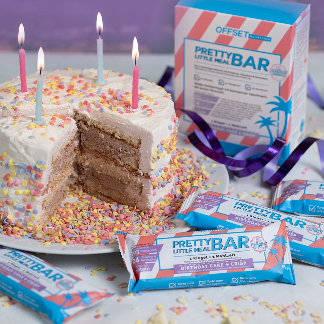 Torte mit bunten Streuseln und Kerzen, daneben Proteinriegel im Geburtstagsdesign.