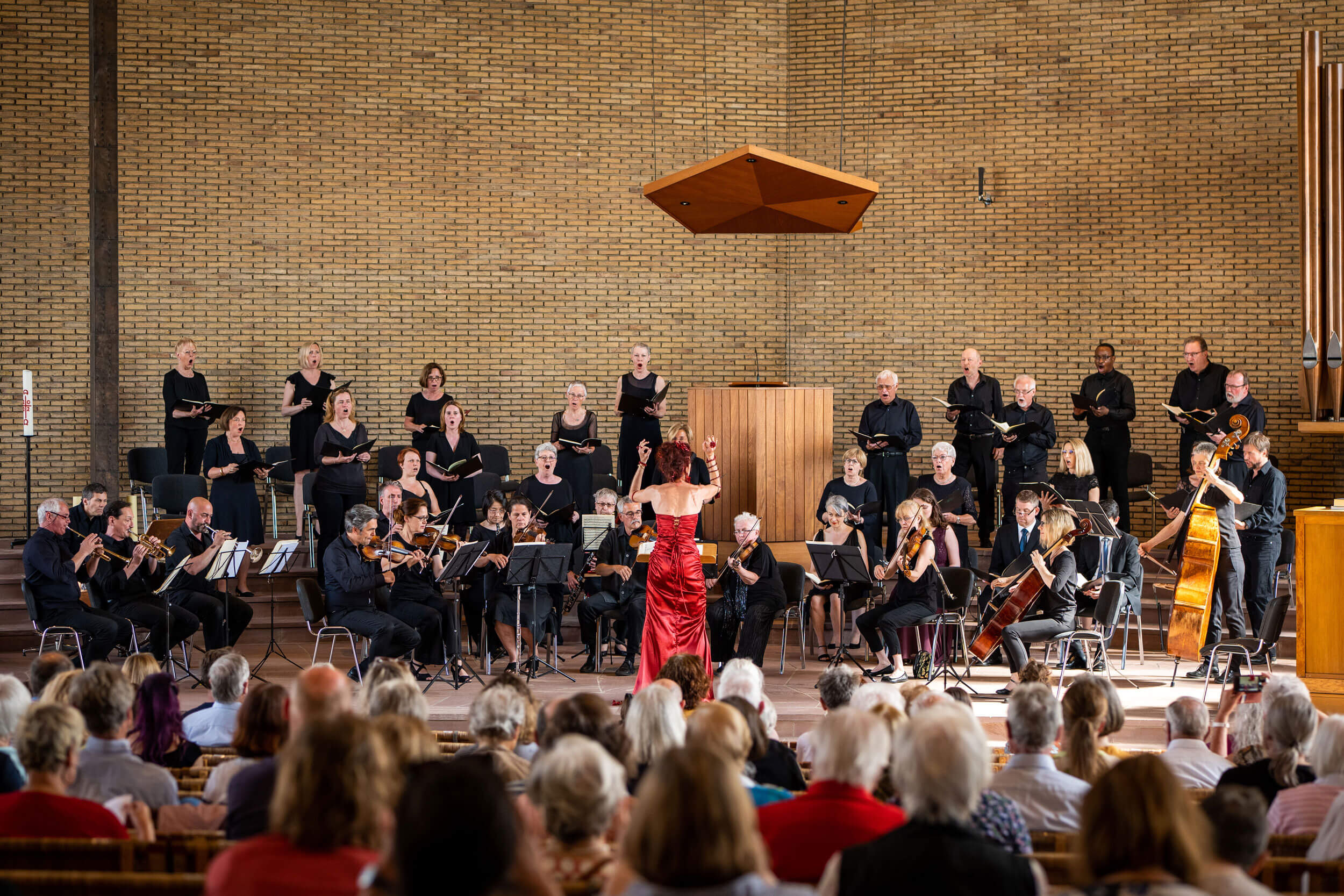 Ein Chor und Orchester treten in einem Saal vor einem begeisterten Publikum auf.
