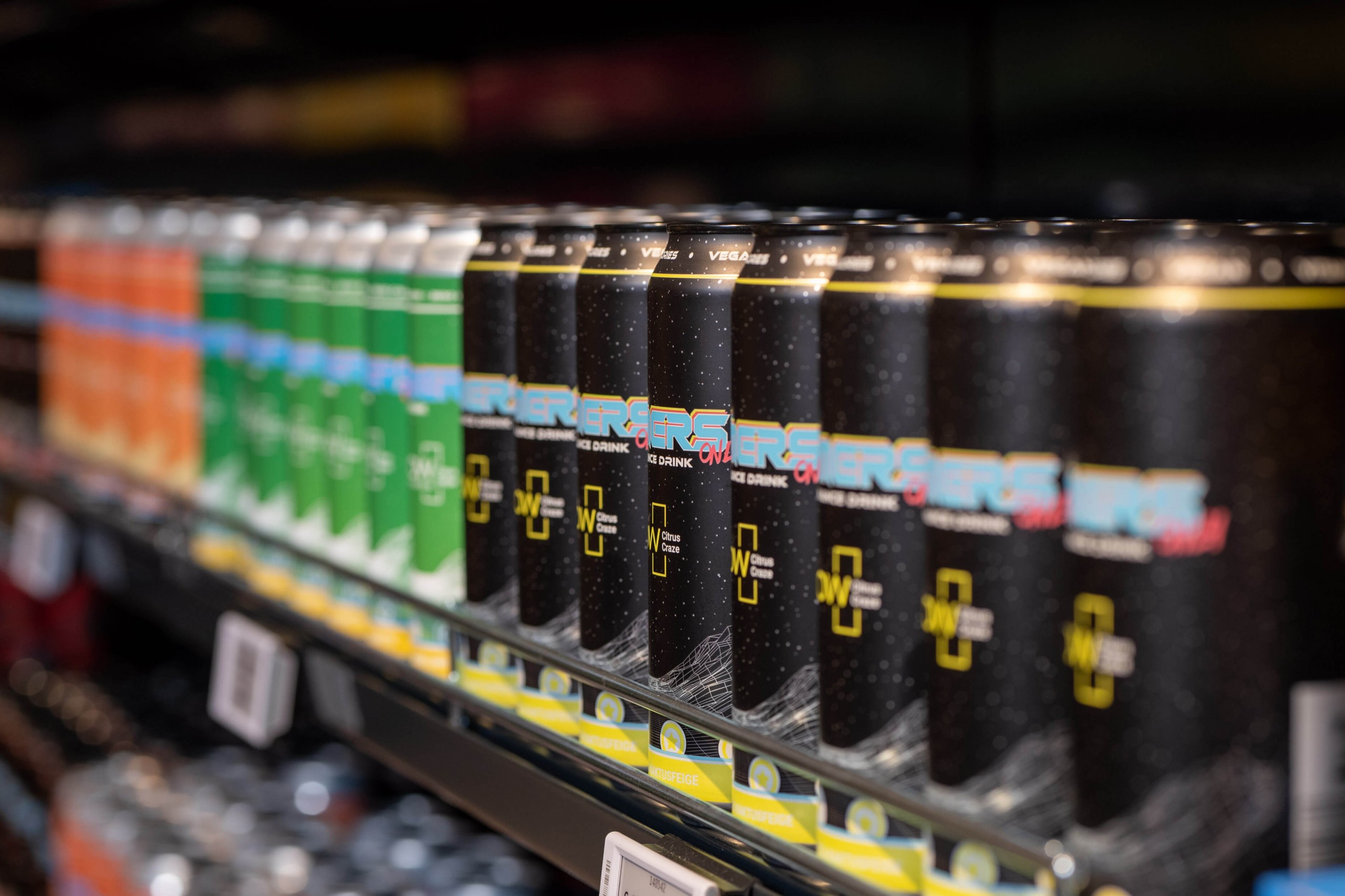 Reihe farbenfroher Energy-Drink-Dosen in einem Verkaufsregal.