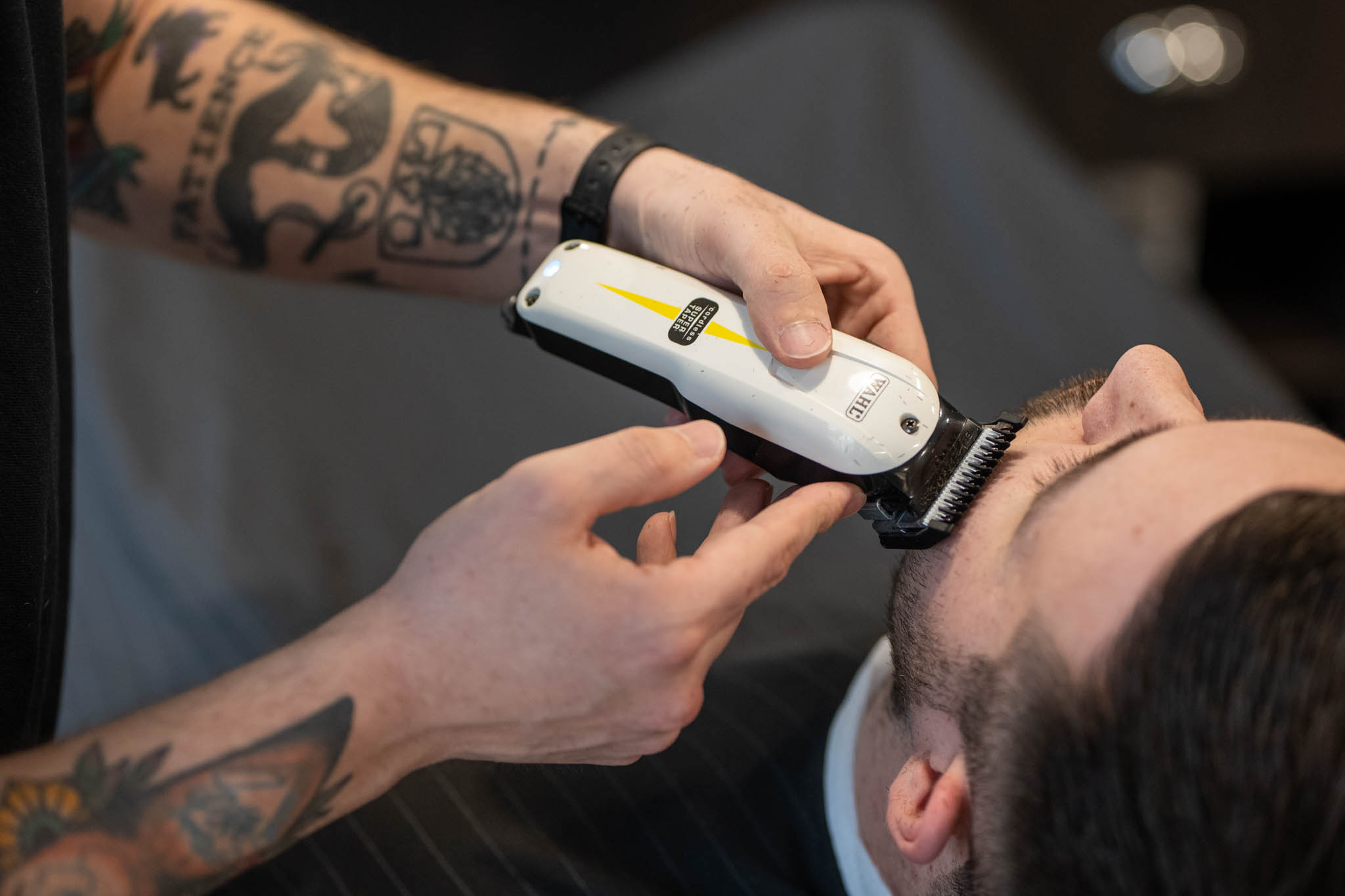 Ein Barbier trimmt den Bart eines Mannes mit einem Haarschneider.